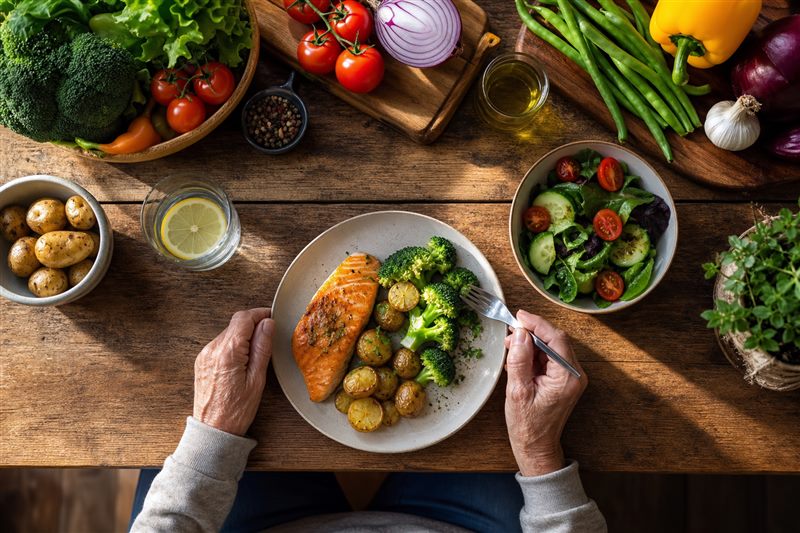 Fresh vegetables and a healthy home-cooked meal prepared on a wooden kitchen table